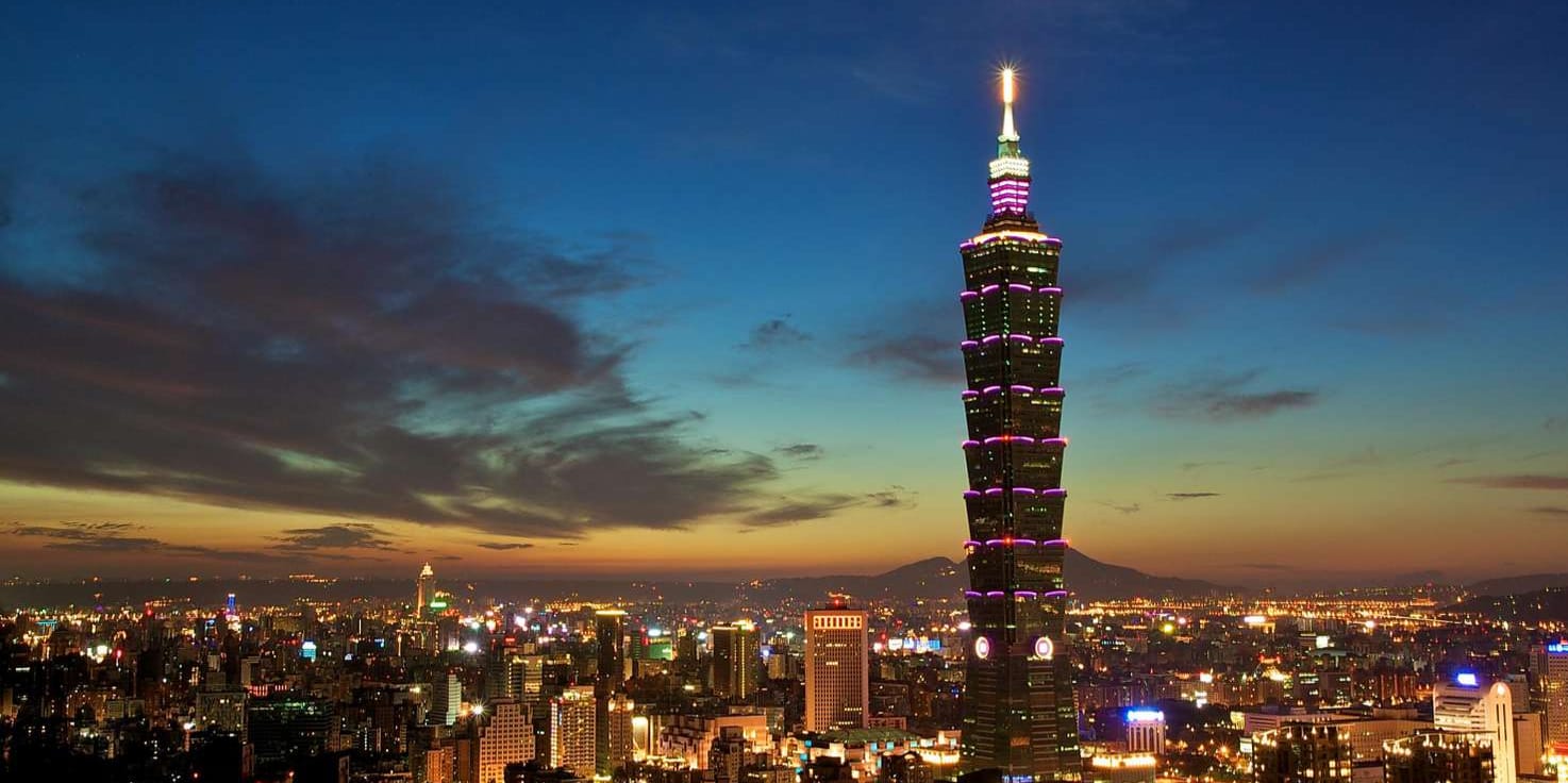 Taipei 101 illuminated at dusk, towering over the city skyline against a dramatic gradient sky in Taiwan.